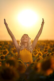 Young attractive woman in a sunflower field at sunset