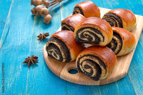 Tasty buns rolls with poppy filling on a blue wooden background.