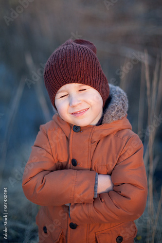 little boy in a red jacket held out his hand, autumn field with dry grass.