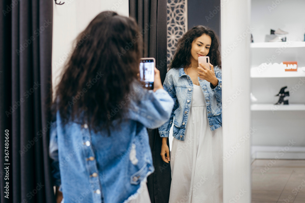 Obraz premium Shopper woman trying clothing dress in clothes store during sale.