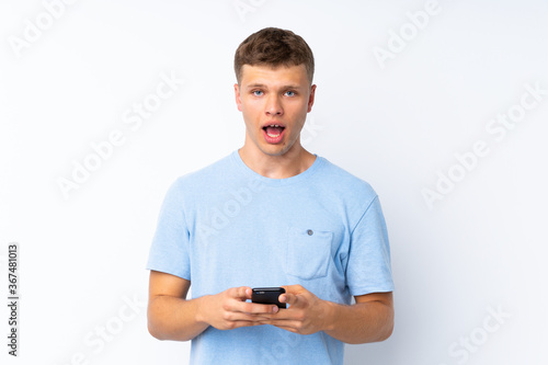 Young handsome man over isolated white background surprised and sending a message
