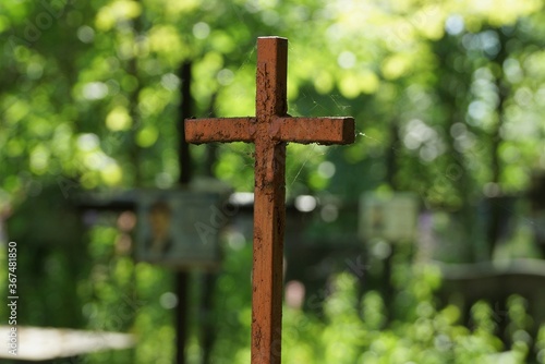 one old brown iron cross in a spider web on a green background in a cemetery