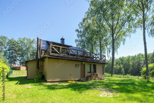 Countryside private house near the green forest. Modern exterior of cottage with terrace. Woodpile near the wall.