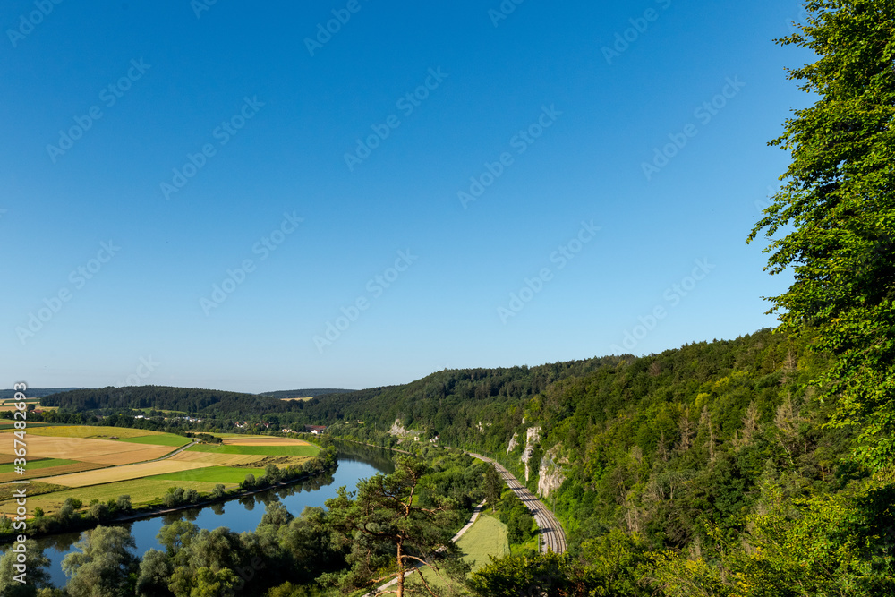 Scenic view over the village Lohstadt and the river danube near Regensburg, Bavaria, Germany with single train track on sunny summer day with clear sky