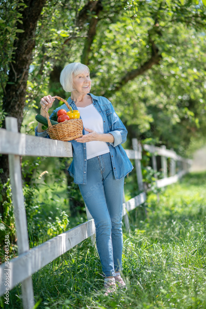Elderly woman holding a basket of fresh vegetables Elderly woman holding a basket of fresh vegetables