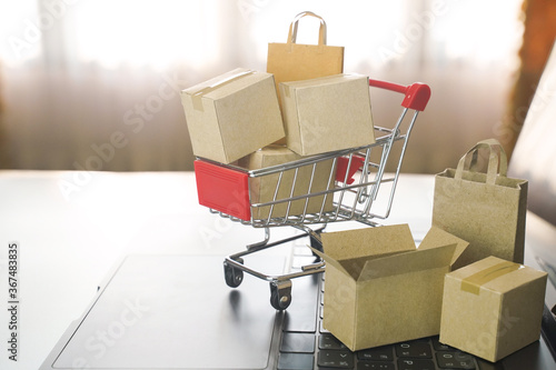 Paper cartons or parcel in the cart on laptop keyboard. Shopping service on online web and offers home delivery. online shopping concept.