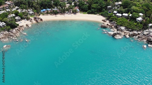 Small houses on tropical island. Tiny cozy bungalows located on shore of Koh Samui Island near calm sea on sunny day in Thailand. Volcanic rocks and cliffs drone top view. © Dogora Sun
