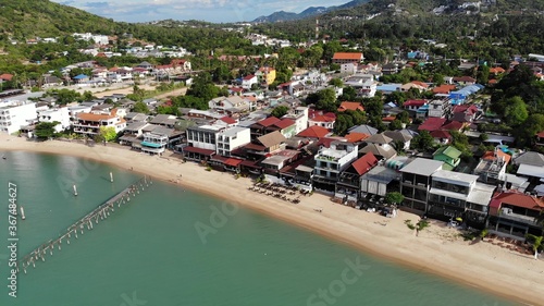 Fisherman village on seashore. Aerial view of typical touristic place on Ko Samui island with souvenir shops and walking street on sunny day. Architecture in asia, local settlement drone view photo