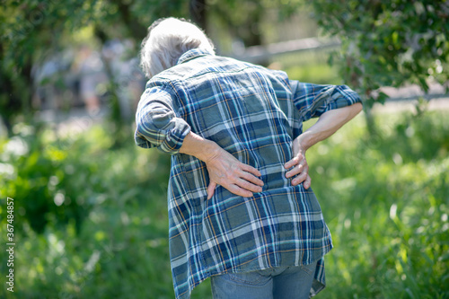 Foto Senior woman having a back pain outdoor