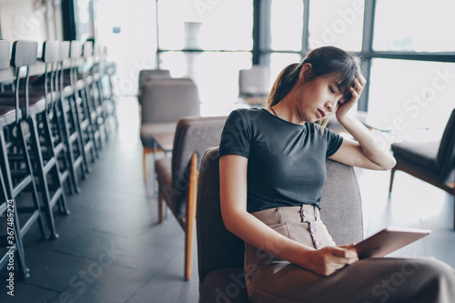Asian businesswoman using tablet at city cafe. She feeling bad between surfing the internet and read news. social distancing concept.