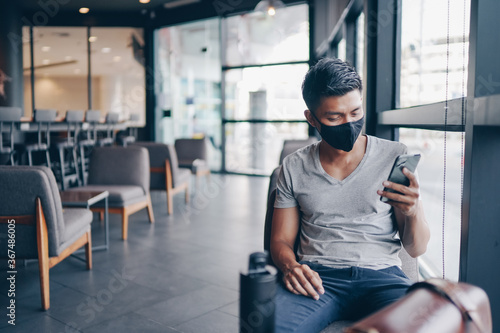 Attractive asian businessman with mask using smartphone at cafe. Drinking coffee and surfing the internet and read news. social distancing concept.