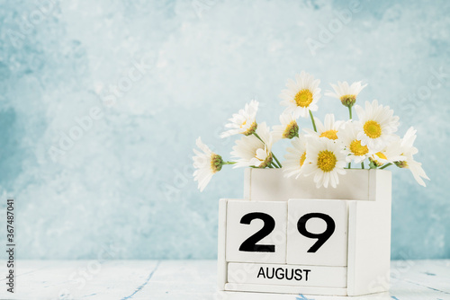 White cube calendar for august decorated with daisy flowers photo