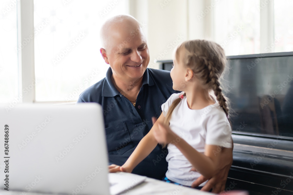Portrait of grandfather and granddaughter doing homework with laptop. Portrait of grandfather and granddaughter doing homework with laptop.