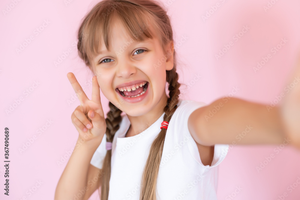 Beautiful little blonde girl with long hair in white T-shirt smiling on a pink background Beautiful little blonde girl with long hair in white T-shirt smiling on a pink background