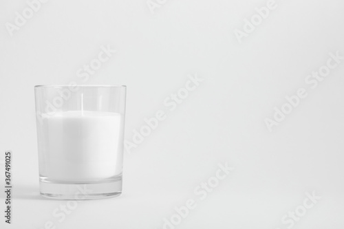 White candle in transparent glass on white background, mock up photo