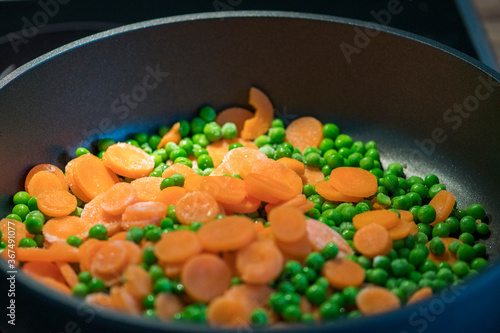 fast cooking peas with carrot slices in the pan