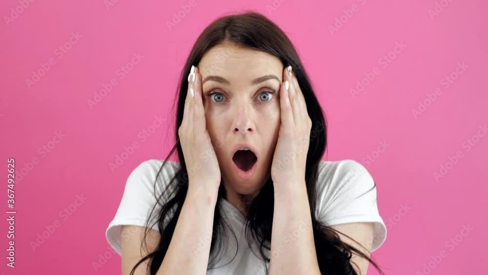 Surprised young, brunette woman keeping mouth open while staring at camera, isolated on pink background. Emotional, attractive female with open mouth is shocked, surprised Surprised young, brunette woman keeping mouth open while staring at camera, isolated on pink background. Emotional, attractive female with open mouth is shocked, surprised