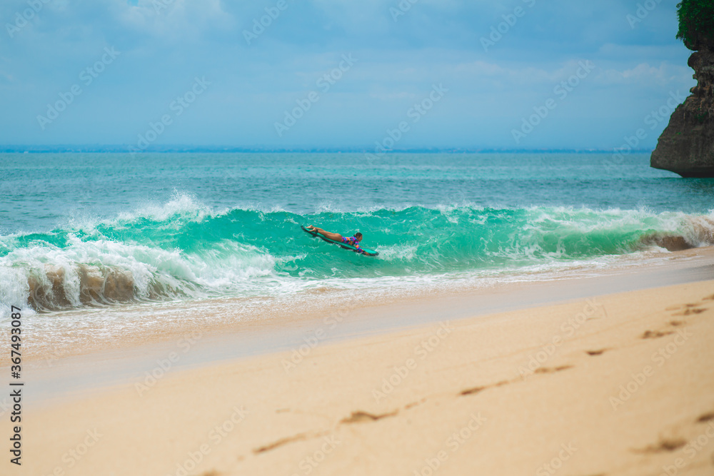 Sexy slim girl riding on surf board in the ocean. Healthy active lifestyle in summer vocation.