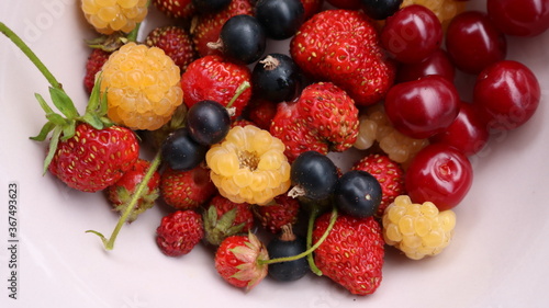 multi-colored variety of ripe berries collected in a summer garden and a mixture lying on a white plate