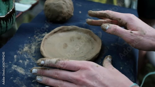 Human hands making a plate from clay.