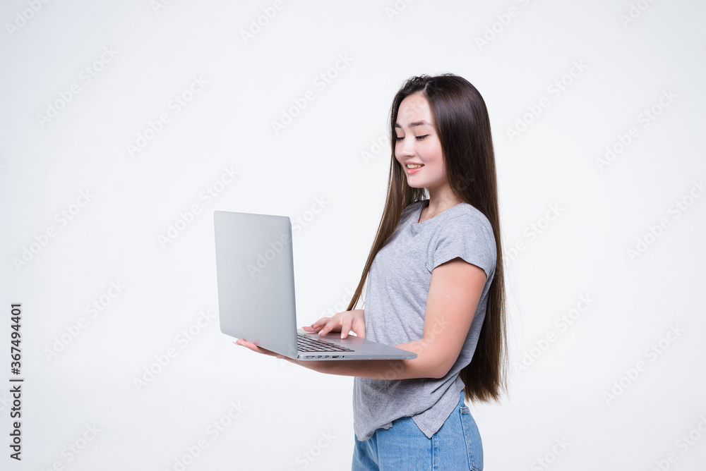 Portrait of a smiling asian woman holding laptop isolated on gray background Portrait of a smiling asian woman holding laptop isolated on gray background