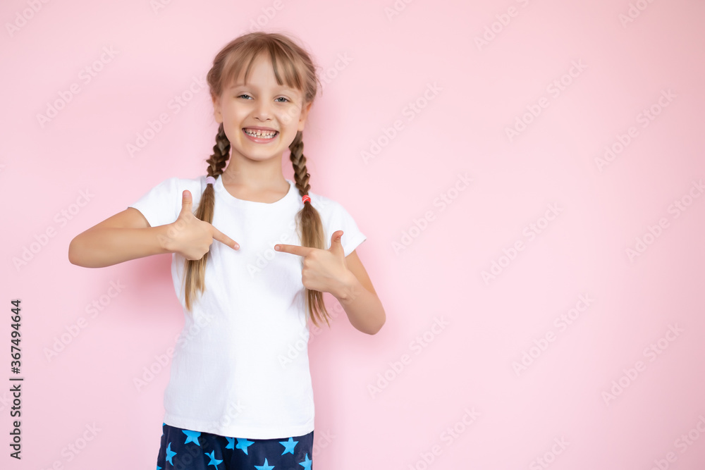Pretty little girl in a white t-shirt smiling on a pink background Pretty little girl in a white t-shirt smiling on a pink background