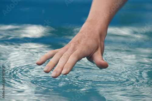 human hand touches the water surface