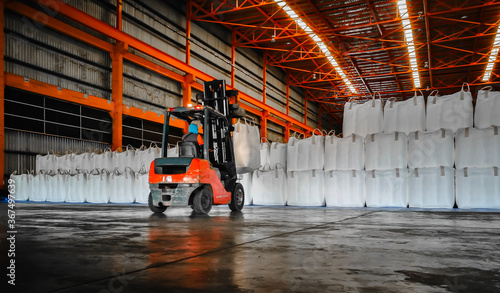 Forklift intake jumbo bags of cargo tapioca starch into warehouse. Bulk sugar cargo handling in bags. © Hor