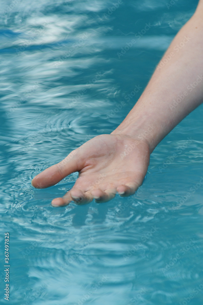 human hand touches the water surface