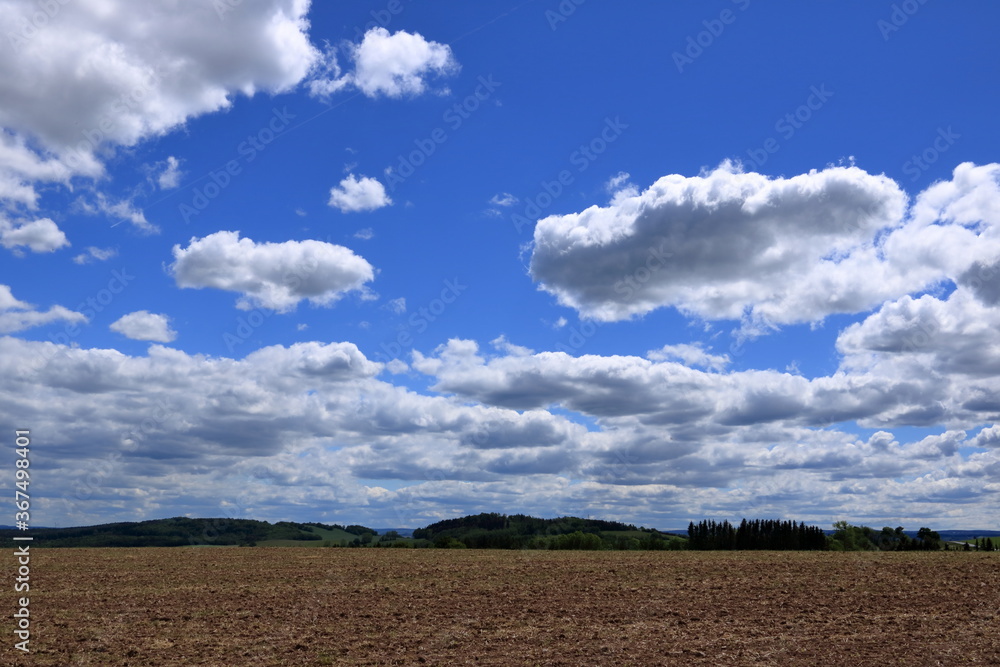 Plowed or Ploughed Field in Countryside and Blue Sky with Clouds over Horizon Plowed or Ploughed Field in Countryside and Blue Sky with Clouds over Horizon
