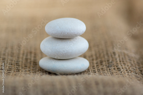 One simplicity stones cairn on jute brown background, group of five light gray pebbles built in tower