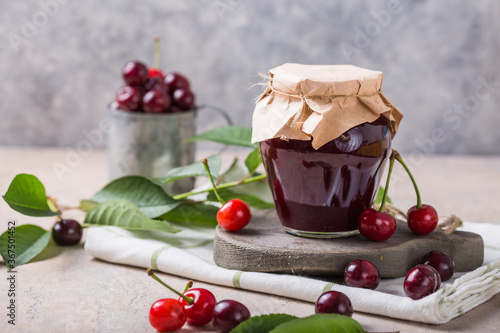 Homemade sweet and sour cherry jam with fresh cherries on light table, copy space photo