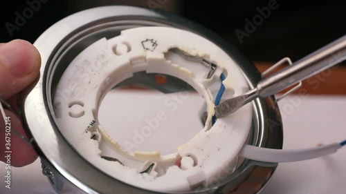 Close-up of a LED broken down lamp dismantled from the ceiling, an electrician using a screwdriver disassembles the lamp, repairing a home electrician. Selective focus, shallow depth of field photo