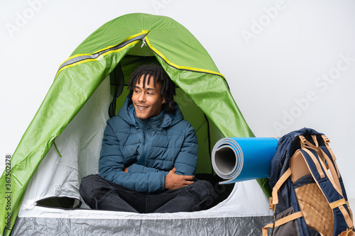 Young african american man inside a camping green tent happy and smiling