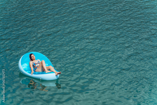 Young woman relaxing at the beach while sunbathing on a floating mattress