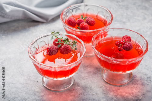 Raspberry jelly garnished with fresh raspberries and thyme on a light background. photo