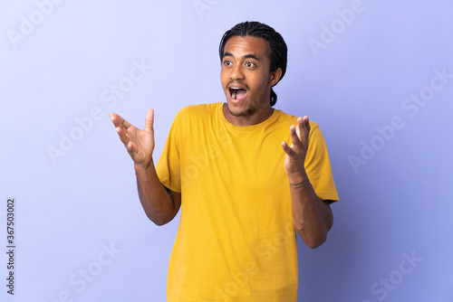 Young African American man with braids man isolated on purple background with surprise facial expression