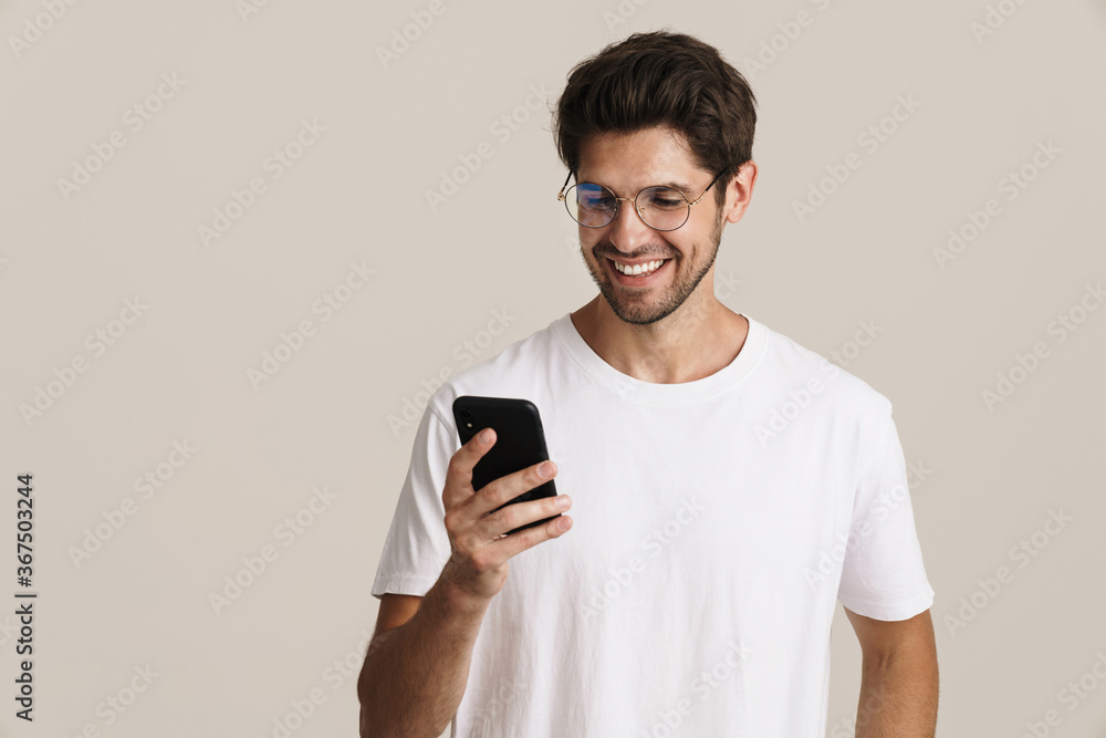 Image of smiling young man in eyeglasses using mobile phone Image of smiling young man in eyeglasses using mobile phone
