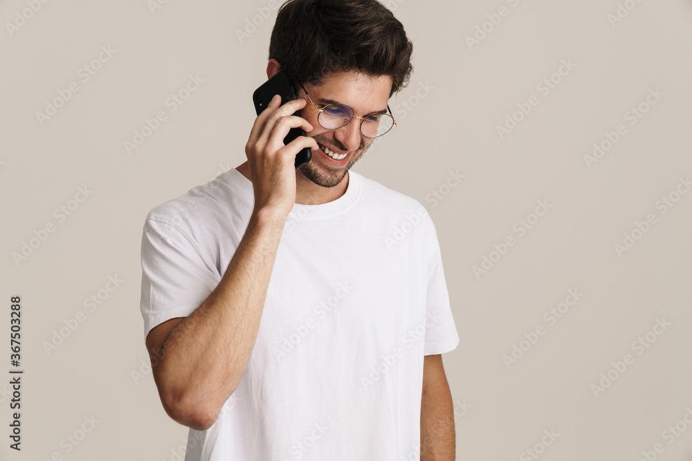 Image of smiling young man in eyeglasses talking on mobile phone Image of smiling young man in eyeglasses talking on mobile phone