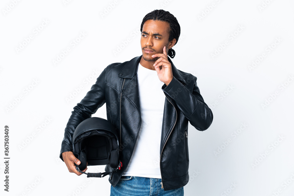 African American man with braids holding a motorcycle helmet isolated on white background thinking an idea while looking up African American man with braids holding a motorcycle helmet isolated on white background thinking an idea while looking up
