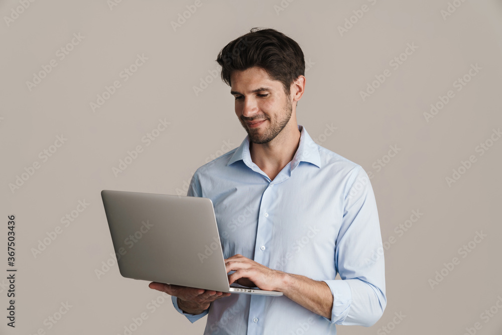 Image of smiling businesslike brunette man working with laptop Image of smiling businesslike brunette man working with laptop