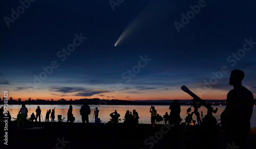 Comet Neowise and people with cameras and telescope silhouetted by the Ottawa river watching and photographing the comet