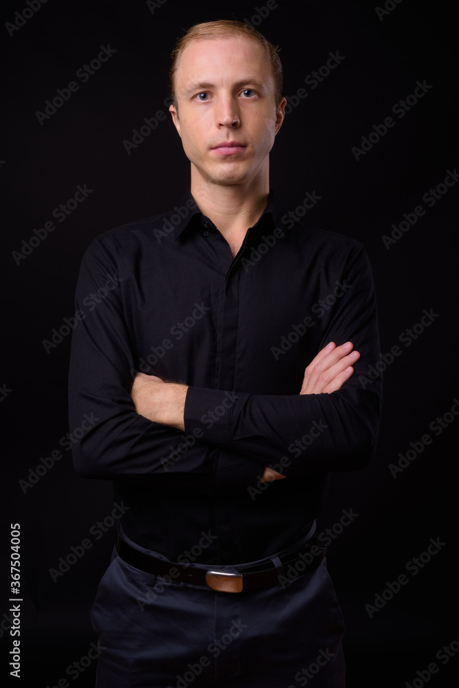 Businessman with blond hair against black background