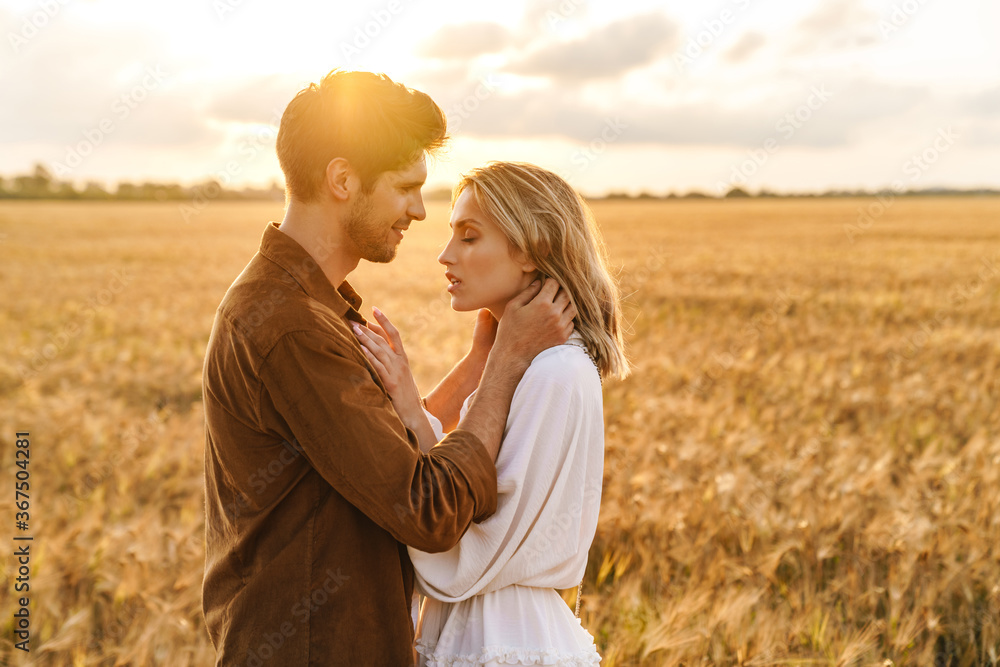 Image of young couple hugging together in golden field on countryside Image of young couple hugging together in golden field on countryside