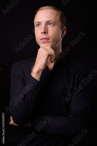 Businessman with blond hair against black background