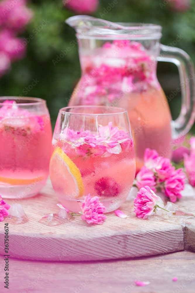 Fresh Rose lemonade or cokctail with ice and fresh roses over natural garden Fresh Rose lemonade or cokctail with ice and fresh roses over natural garden