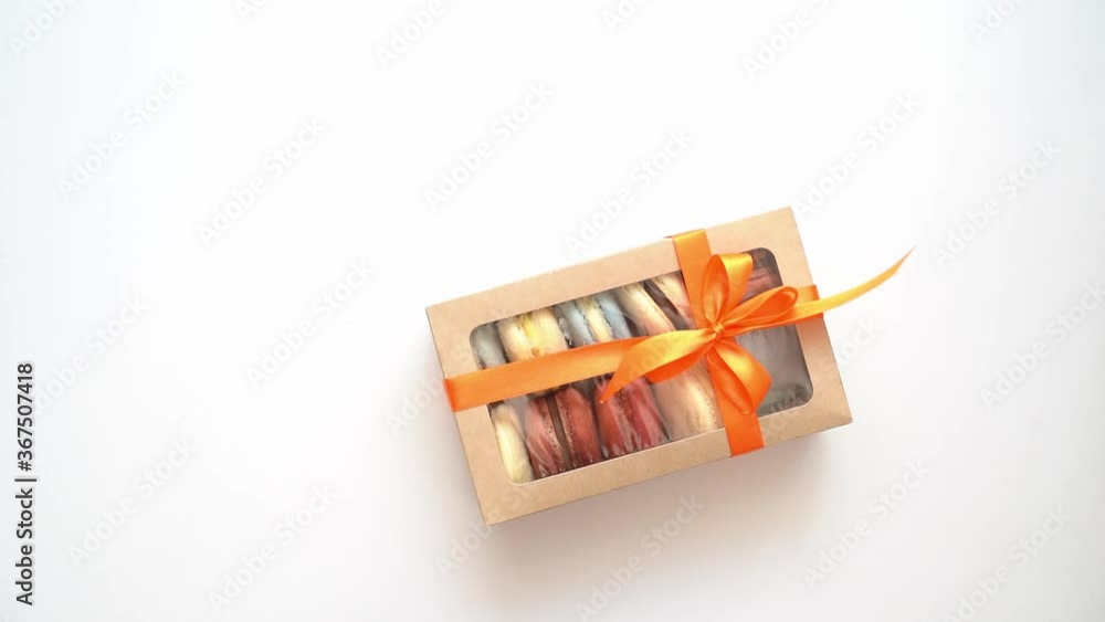 pack with ribbon and inside macarons enters frame on white background. pack with ribbon and inside macarons enters frame on white background.
