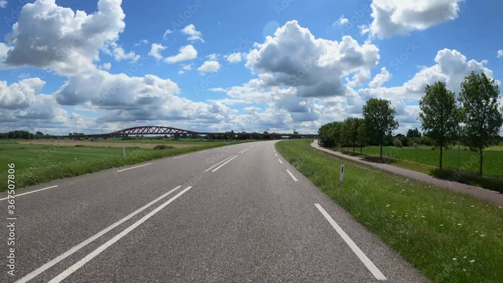 POV Driving along river IJssel with polder landscape, train bridge and beautiful clouds POV Driving along river IJssel with polder landscape, train bridge and beautiful clouds