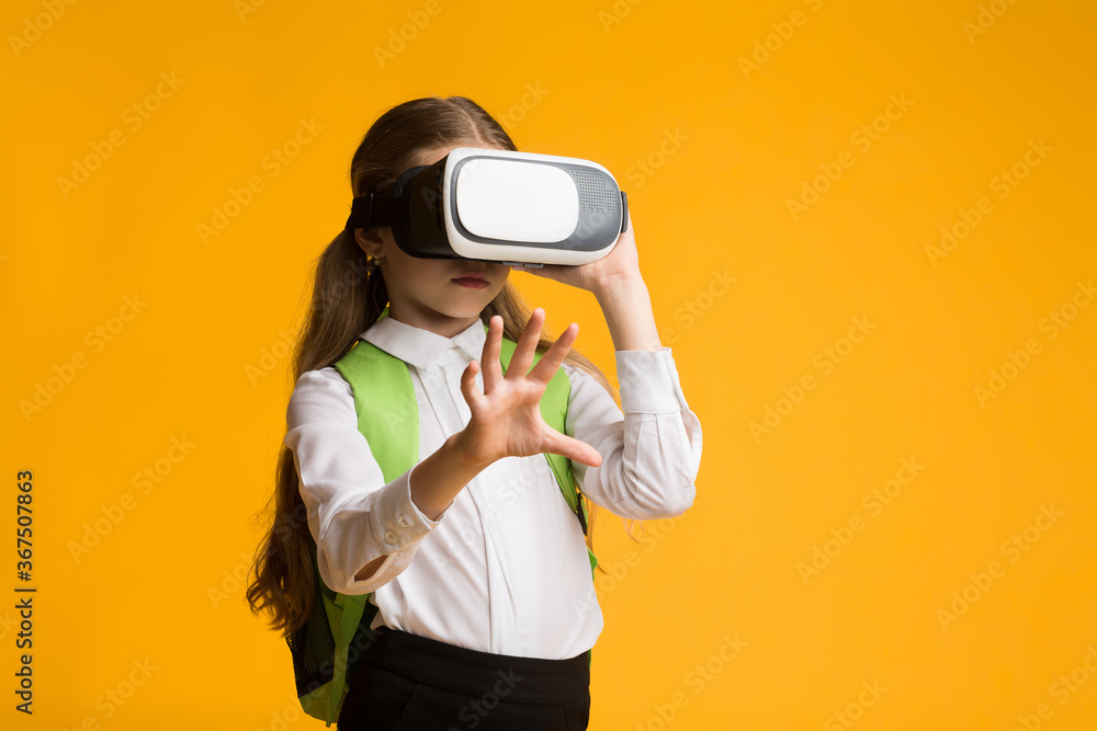 Obraz premium Schoolgirl Wearing VR Glasses Experiencing Virtual Reality In Studio