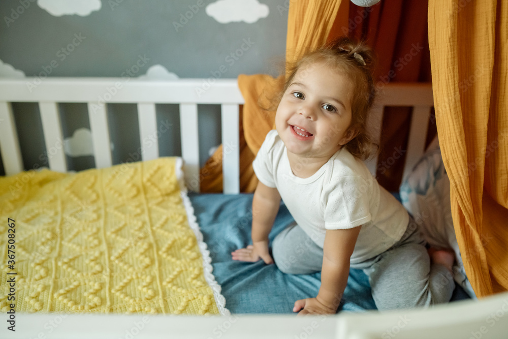 Little cute curly haired girl two years old playing in her canopy bed at home Little cute curly haired girl two years old playing in her canopy bed at home